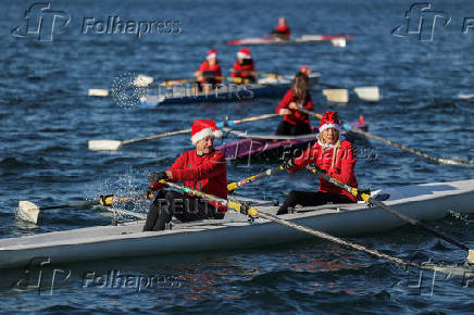 People in Santa Claus costumes row off the seafront of Thessaloniki