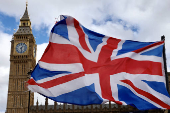 A Union Jack flag flutters in the wind near Big Ben and Parliament in Parliament Square in London