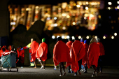 Migrants walk towards a Red Cross tent to be treated after disembarking from a Spanish coast guard vessel, in the port of Arguineguin