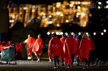 Migrants walk towards a Red Cross tent to be treated after disembarking from a Spanish coast guard vessel, in the port of Arguineguin