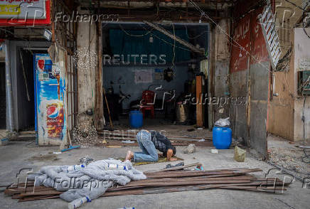 A man prays outside his shop damaged in an Israeli strike, after the ceasefire between Israel and Hezbollah, in Tyre