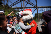 Guatemalan firefighter dressed as Santa Claus rappels down the Vacas Bridge to give toys to children, in Guatemala City