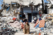 Palestinians sit amidst the rubble of buildings destroyed during the Israeli offensive, amid a ceasefire between Israel and Hamas, in Rafah