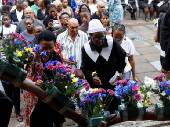 People place flowers on a cross during a silent Good Friday procession in Durban