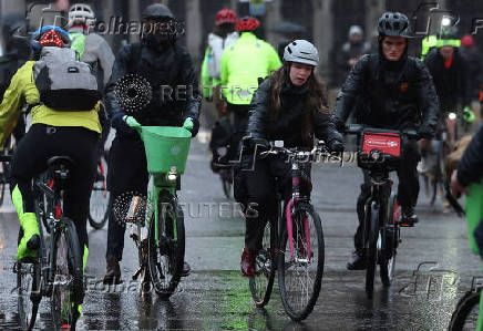 Cyclists ride in rain during morning rush-hour near Houses of Parliament, in London