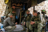 Ukrainian servicemen speak to each other next to a dugout at their position in a front line in Donetsk region