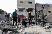 Palestinians inspect damage at the site of an Israeli strike on a house, at Nuseirat refugee camp