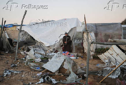 Palestinians inspect the damage at a tent camp sheltering displaced people, in Khan Younis