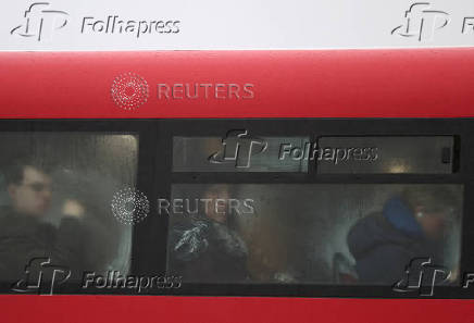 Commuters sit on a bus as it rains during the morning rush-hour in London