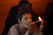 A Naga Sadhu or Hindu holy man smokes inside his tent during the 