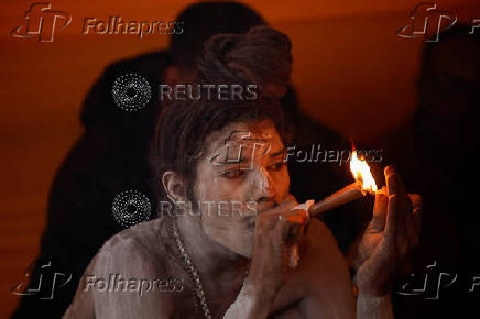 A Naga Sadhu or Hindu holy man smokes inside his tent during the 