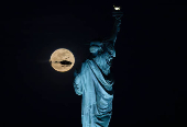 Lua Rosa (primeira lua cheia da primavera) iluminada em 100 por cento surge atrs da Esttua da Liberdade na cidade de Nova York