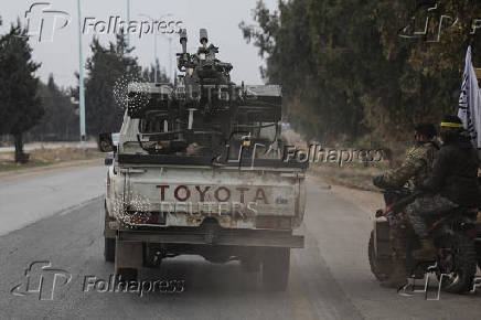 Rebel fighters sit on a motorcycle in Homs countryside