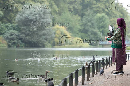 Birds land on a person at St James's Park in London