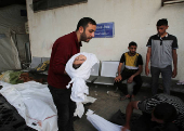 A man carries the body of a Palestinian child killed in Israeli strikes, in Rafah