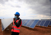 FILE PHOTO: A worker walks past solar panels at Centragrid power plant in Nyabira