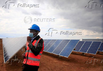 FILE PHOTO: A worker walks past solar panels at Centragrid power plant in Nyabira