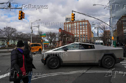 People are taken for a test drive in a Tesla Cybertruck near a Tesla showroom in New York City