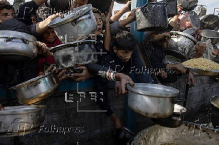 Displaced Palestinians collect donated food in Khan Yunis, southern Gaza