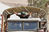 An Israeli soldier gestures from a military truck as it maneuvers near the Israel-Gaza border