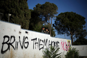 Israeli police officers stand next to graffiti in support of hostages kidnapped in October 7 attack on Israel by Hamas, in Jerusalem
