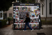 Woman walks past posters of hostages kidnapped during the deadly October 7 2023 attack by Hamas, in Tel Aviv