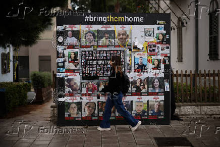 Woman walks past posters of hostages kidnapped during the deadly October 7 2023 attack by Hamas, in Tel Aviv