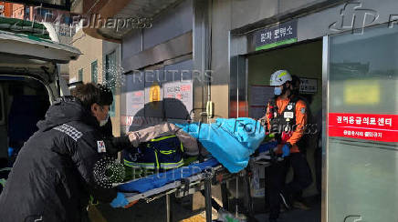 A passenger who was rescued from an aircraft which drove off runway at Muan International Airport is carried to a hospital in Mokpo