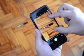 Foto mostrando a tela de um celular sendo segurado com a cmera ligada