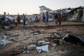 Palestinians inspect the damage at a tent camp sheltering displaced people, in Khan Younis