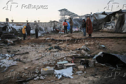 Palestinians inspect the damage at a tent camp sheltering displaced people, in Khan Younis