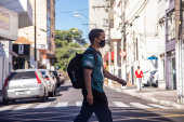 Rapaz com mscara de proteo realiza travessia em faixa de pedestre