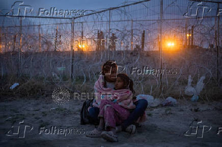 Migrant mother guards daugther while searching for entry into the U.S. from Mexico