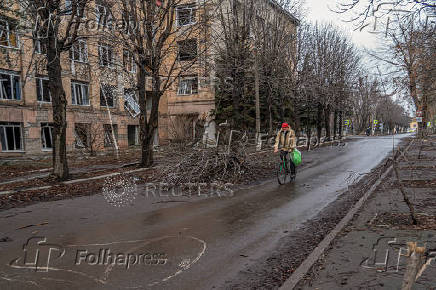 Resident rides a bicycle past a building damaged by Russian military strikes in Pokrovsk