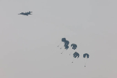 An aircraft drops humanitarian aid packages over the Gaza Strip, as seen from Israel