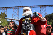 Guatemalan firefighter dressed as Santa Claus rappels down the Vacas Bridge to give toys to children, in Guatemala City