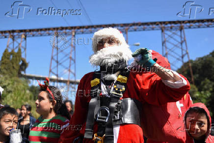 Guatemalan firefighter dressed as Santa Claus rappels down the Vacas Bridge to give toys to children, in Guatemala City