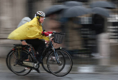 Cyclists ride in rain during morning rush-hour near Houses of Parliament, in London