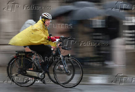 Cyclists ride in rain during morning rush-hour near Houses of Parliament, in London