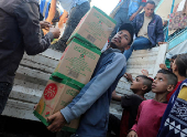 FILE PHOTO: Palestinians distribute aid at a shelter center in Deir Al-Balah
