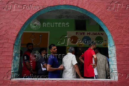 People wait in line outside a polling station to vote during the state assembly elections, in Karnal