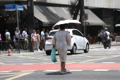 Forte calor faz pedestres se protegerem do sol