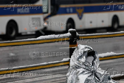 A woman leans on a railing to rest during  a protest against the impeached South Korean President Yoon Suk Yeol near his official residence on a snowy day in Seoul