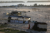 Palestinians gather on a beach near shelters damaged during the Israeli offensive, in Gaza City