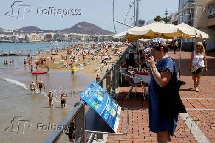 A tourist looks at an information panel on Las Canteras Beach in Las Palmas de Gran Canaria