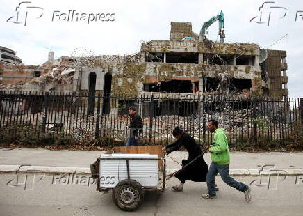 FILE PHOTO: People push carts in front of the remains of the former Chinese embassy during its demolition in Belgrade