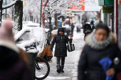 A person walks along the sidewalk whilst on a video call during the city's first snowfall of the season, on the first day of winter in the Queens borough of New York City