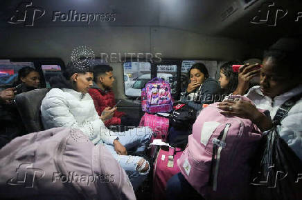 Migrants sit in a van which would take them to a shelter, at El Chaparral border crossing after their CBP One app asylum appointment was cancelled on the day of U.S. President Donald Trump's inauguration, in Tijuana