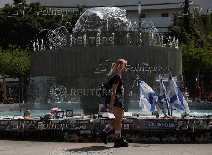 A woman walks past memorabilia and pictures of the hostages kidnapped in the deadly October 7 attack on Israel by the Palestinian Islamist group Hamas from Gaza, at Dizengoff Square, in Tel Aviv