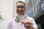 Transgender activist Henry Tse collects his new male identity card in Hong Kong